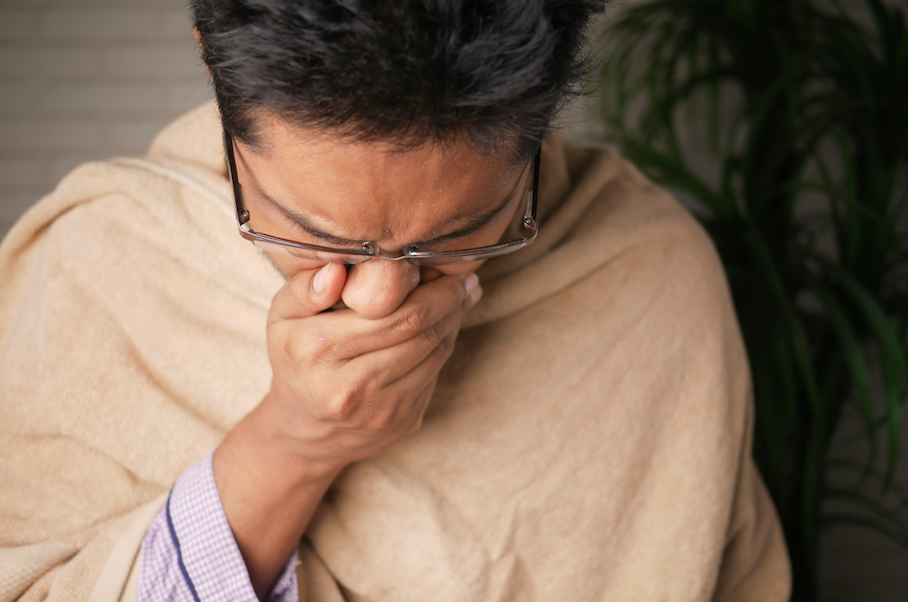 Man coughing while covering his mouth