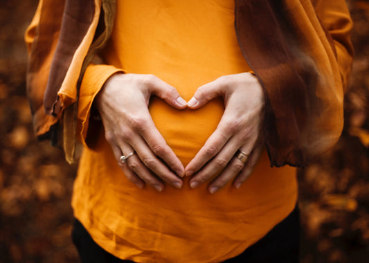 Woman with hands forming a heart shape in front of belly representing good gut health