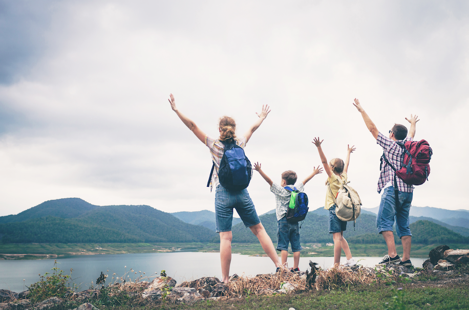 Healthy family hiking together and celebrating the view of a lake