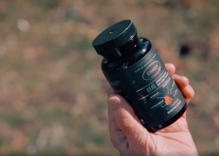 Hand grasping a bottle of Real House Canada Wild Canadian Chaga supplements